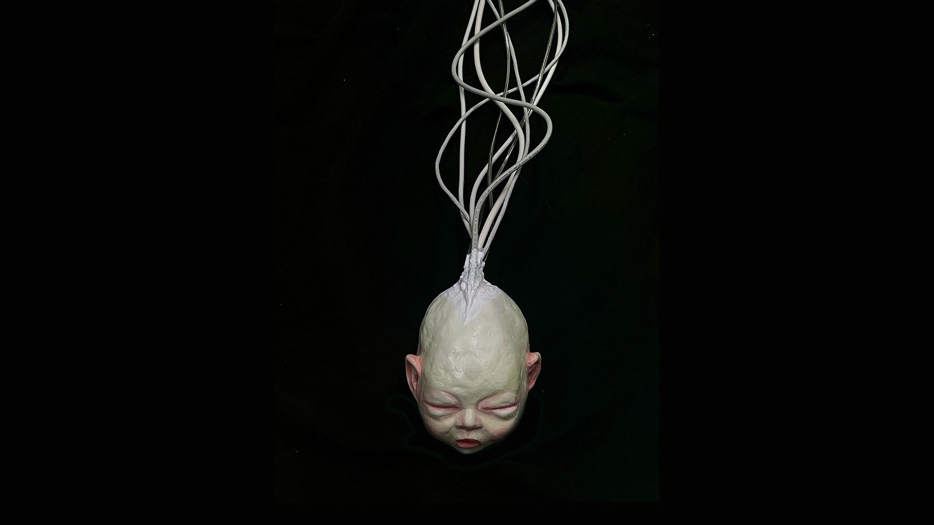 Infant head sculpted of painted air dried clay
