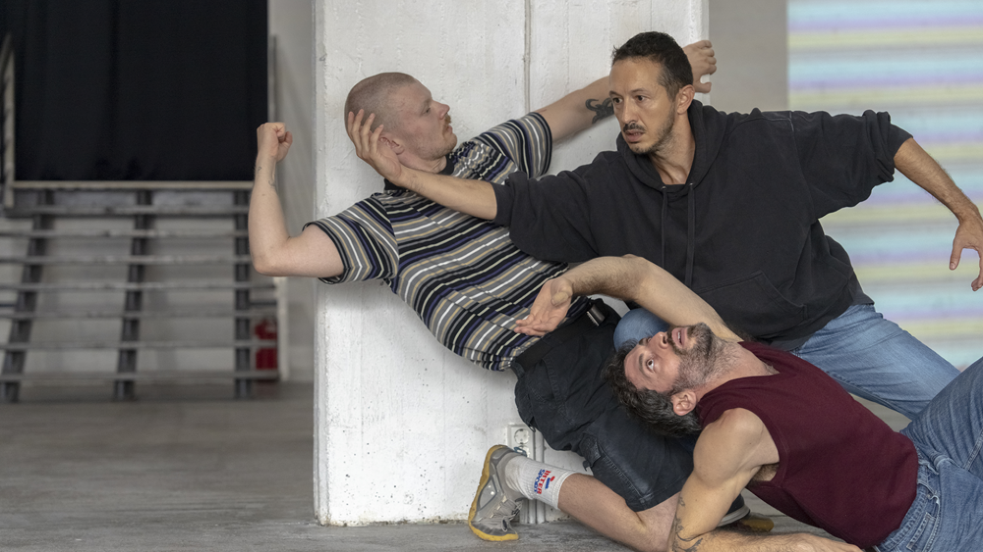 3 artists performing against a white column
