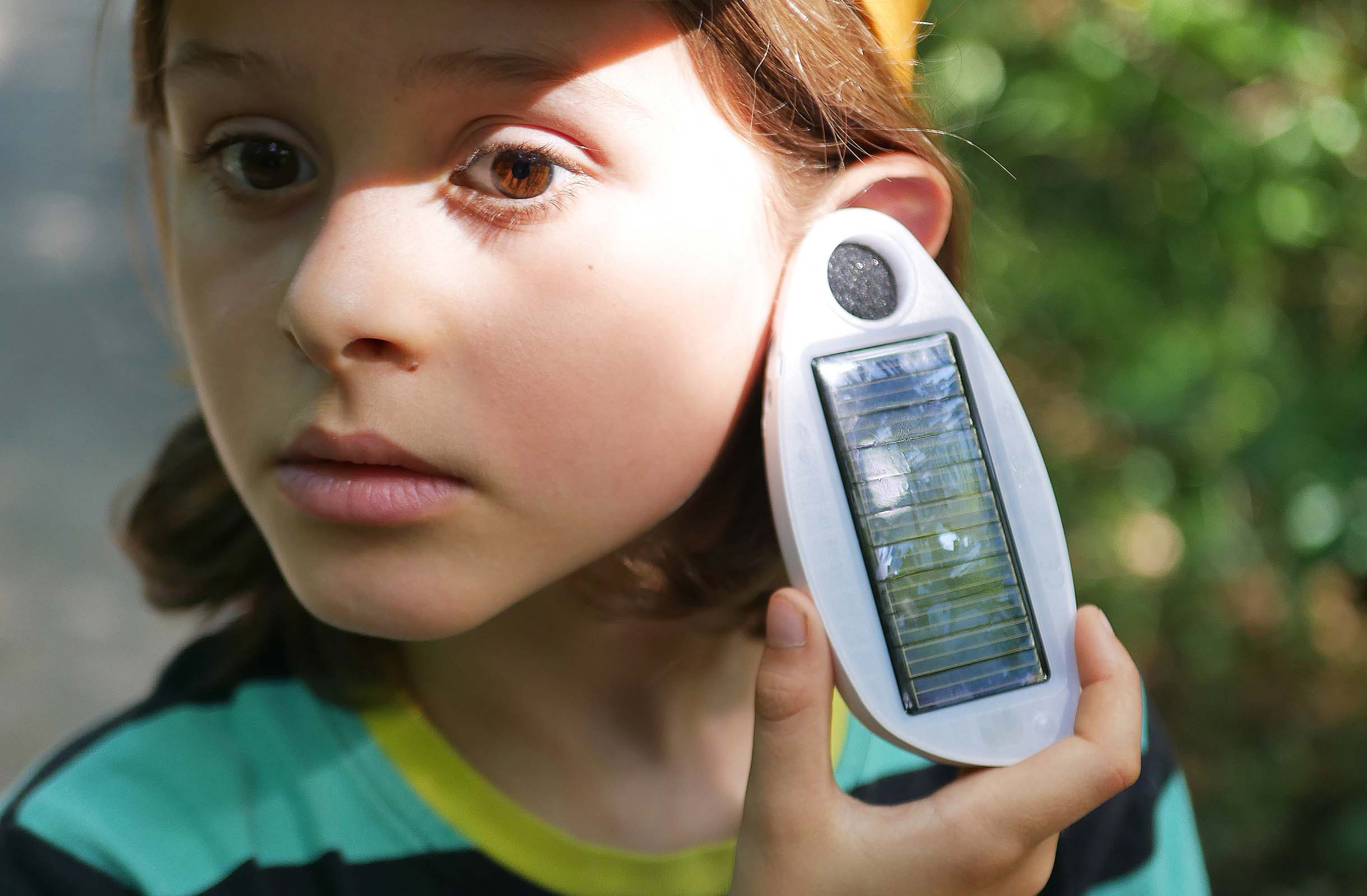 Boy listening to solar energy using a "solar ear".