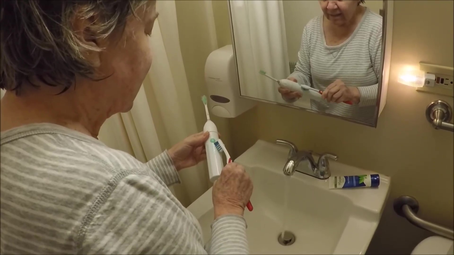 An elder lady forgets how to use toothbrush.