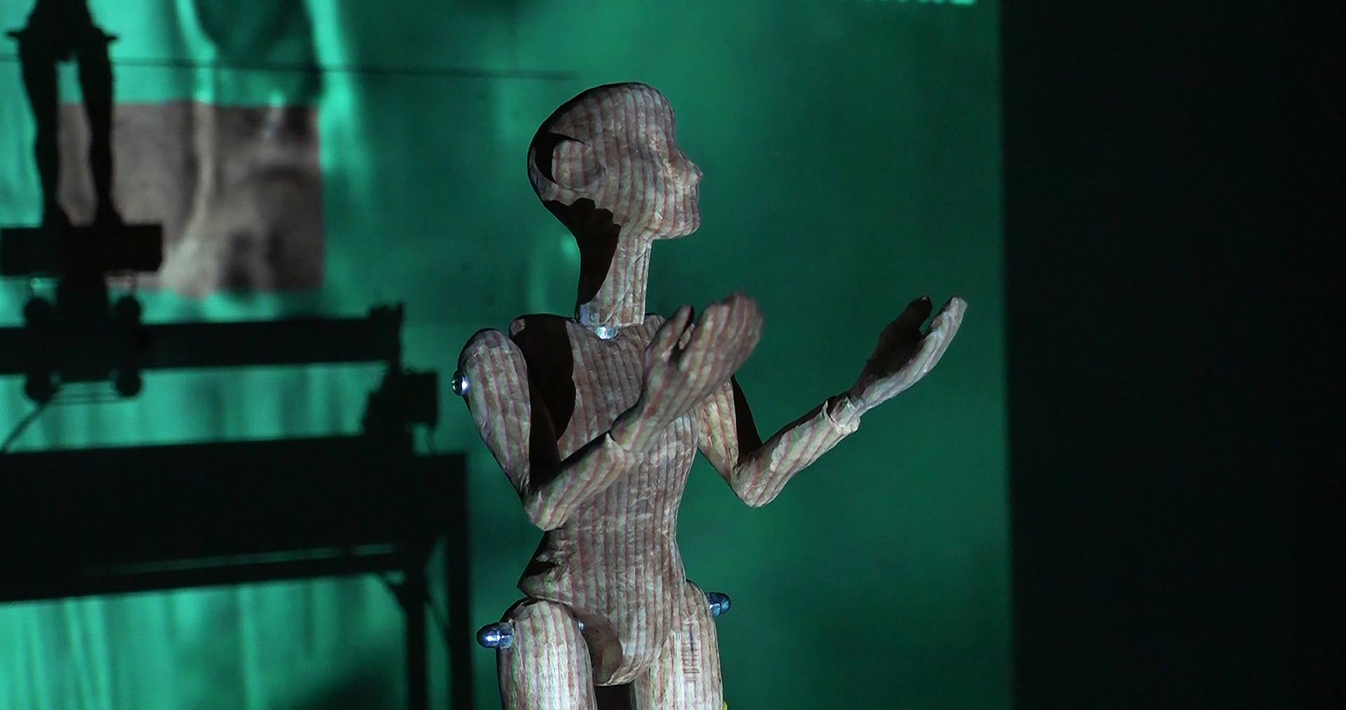 Wooden puppet with arm raised &amp;amp;amp; a projected on to