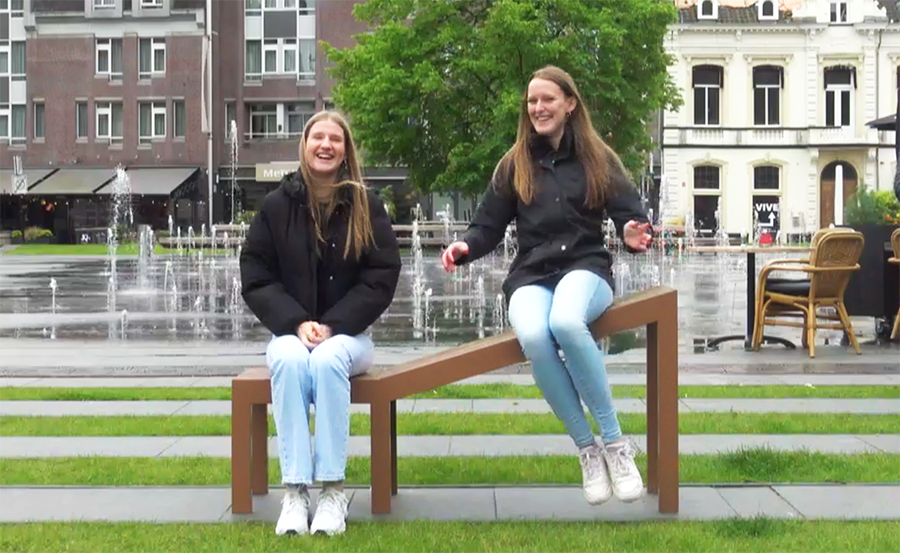 Two girls using the social bench in public